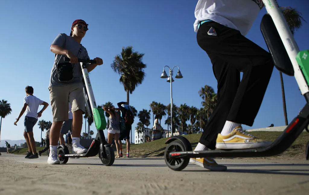 People ride Lime shared dockless electric scooters along Venice Beach in Los Angeles, California on Aug. 13, 2018. (Mario Tama/Getty Images)