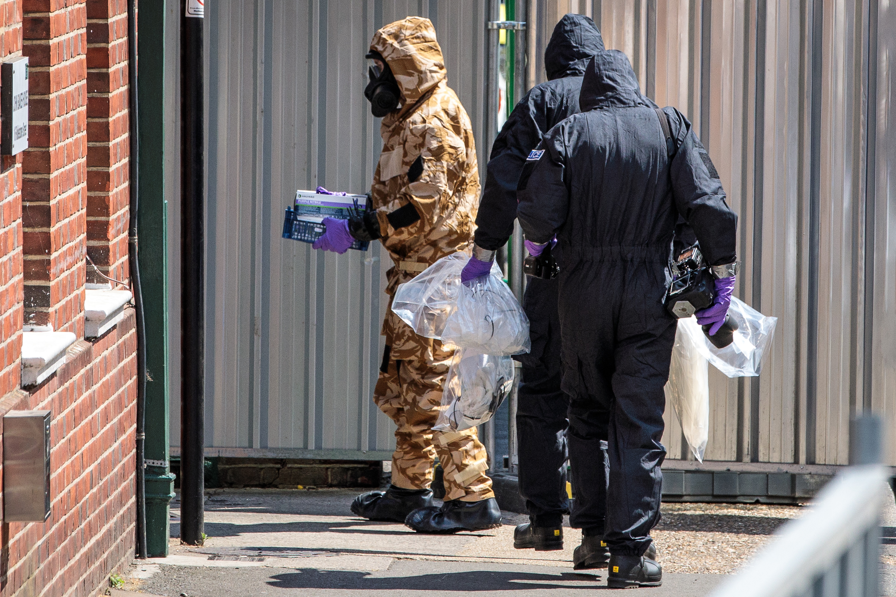 Workers in haz-mat suits search a residence