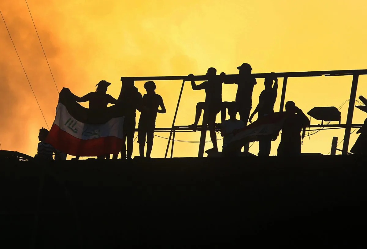 Protesters raise an Iraqi flag over the Basra Government building during a demonstration demanding better public services and jobs in Basra, 340 miles (550 km) southeast of Baghdad, Iraq, on Sept. 7, 2018. (AP Photo/Nabil al-Jurani)