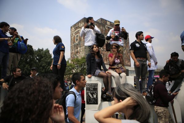 People surround a sign reading in Spanish "Neither porros, nor disappearances, nor murders; injustice," as thousands of students at Mexico's National Autonomous University protest to demand an end to violence by groups of thugs known as "porros," who are often registered but don't attend classes, at the University's main campus in Mexico City, Wednesday, Sept. 5, 2018. Students at Mexico's largest university have gone on strike after a campus attack against protestors on Monday, in which two students were seriously injured. (AP Photo/Rebecca Blackwell)