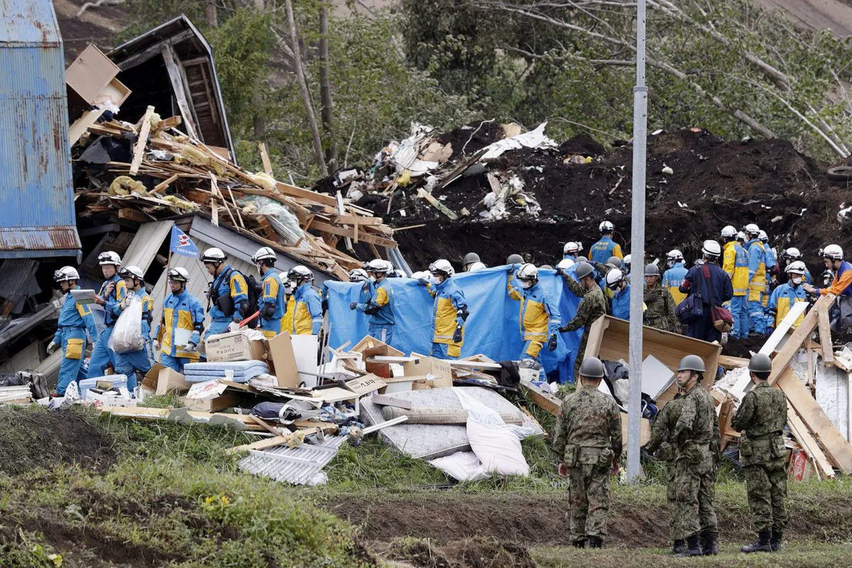 Police officers and members of the Japan Self-Defense Forces (JSDF) carry a missing person found from an area damaged by a landslide caused by an earthquake in Atsuma town, Hokkaido, northern Japan, on Sept. 8, 2018. (Mandatory credit Kyodo/via Reuters)
