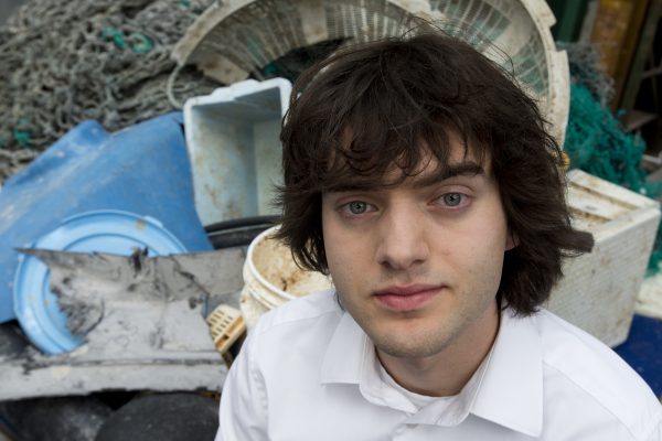 Boyan Slat poses next to a pile of plastic