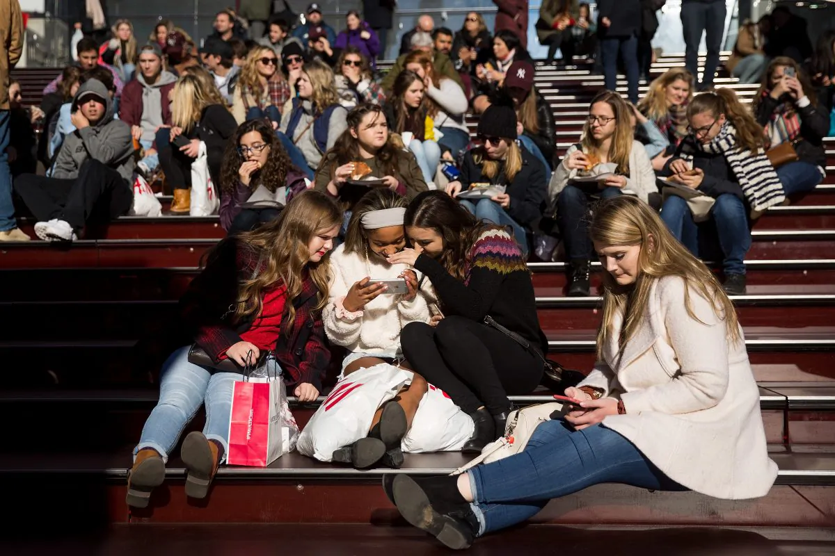 A group of teens look at a photograph they took on a smartphone in Times Square in New York City on Dec. 1, 2017. (Drew Angerer/Getty Images)
