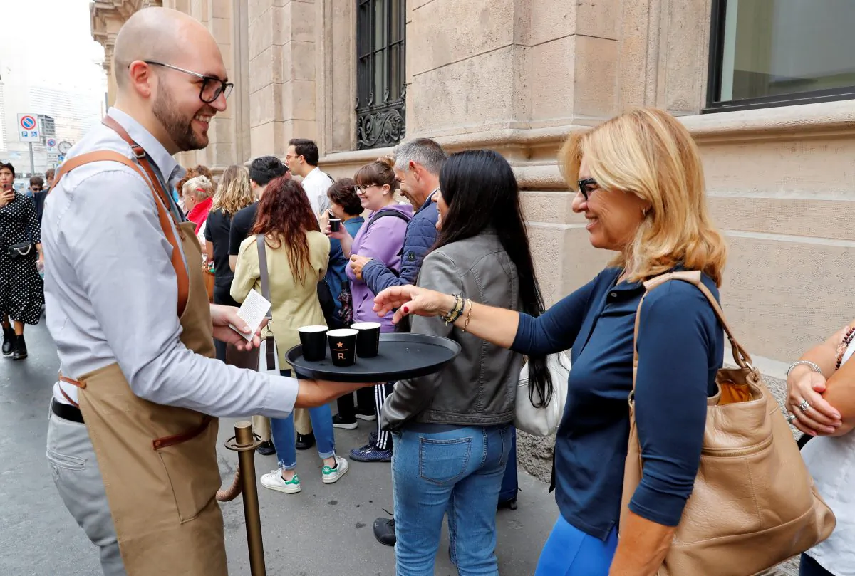 A staff member of Starbucks Reserve Roastery offers coffee to the customers in line on opening day in downtown Milan, on Sept. 7, 2018. (Reuters/Stefano Rellandini)
