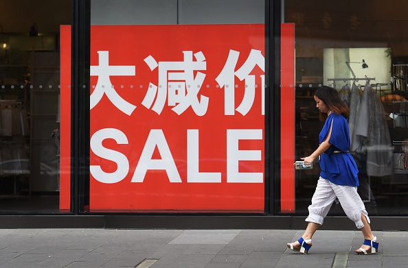 A woman walks past a sale sign at a fashion outlet in a shopping mall in Beijing on July 15, 2015. (GREG BAKER/AFP/Getty Images)