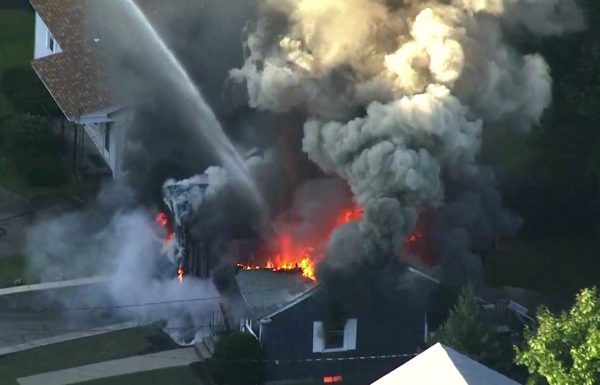 Flames consume the roof of a home in Lawrence