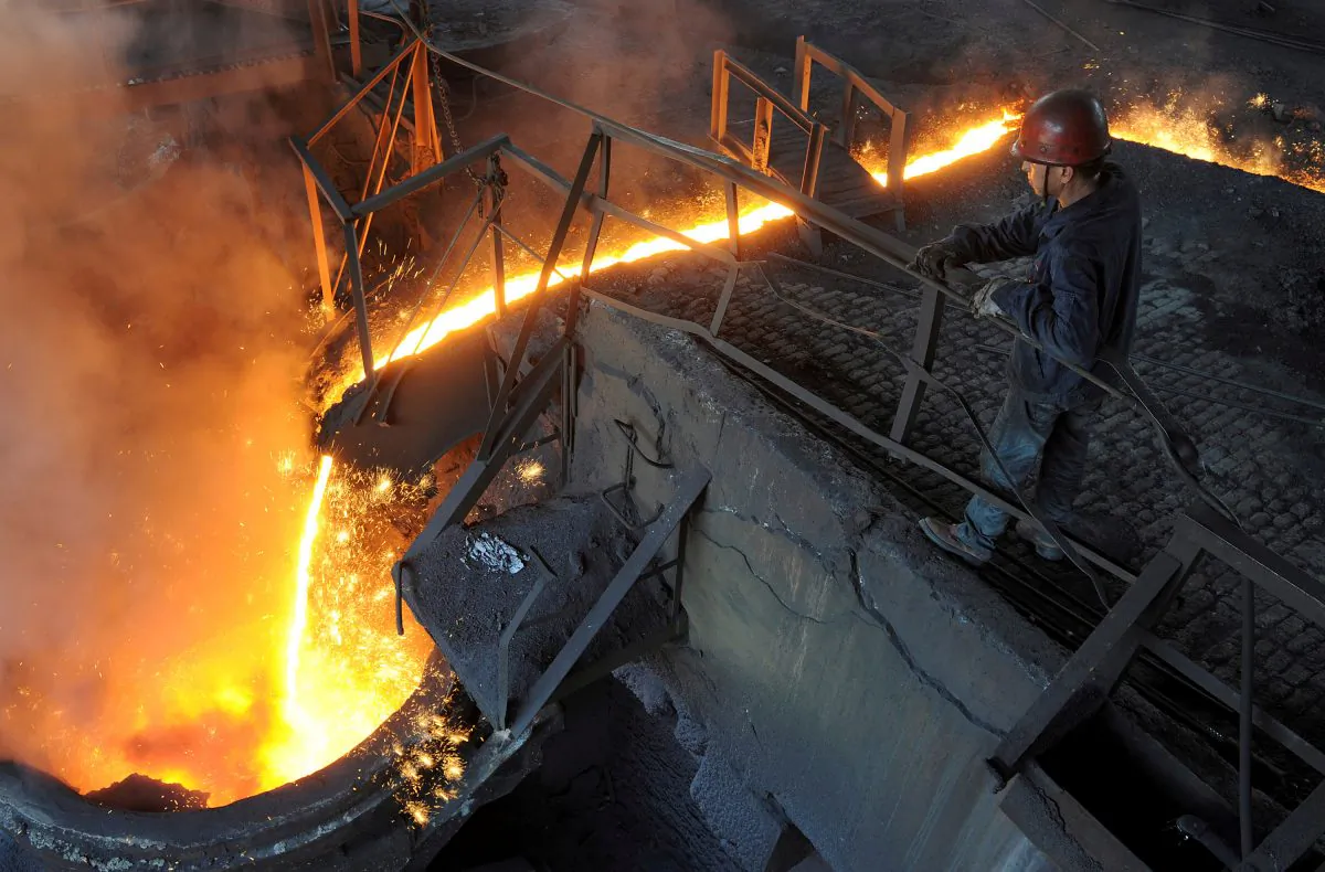 A worker monitors molten iron pouring into a furnace at a steel manufacturing plant in Hefei City, Anhui Province, China, on August 15, 2012. (Stringer/Reuters)