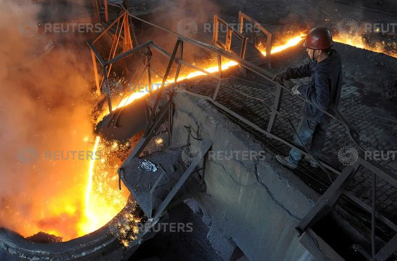 A worker monitors molten iron pouring into a furnace at a steel manufacturing plant in Hefei City, Anhui Province, China, on August 15, 2012. (Stringer/Reuters)