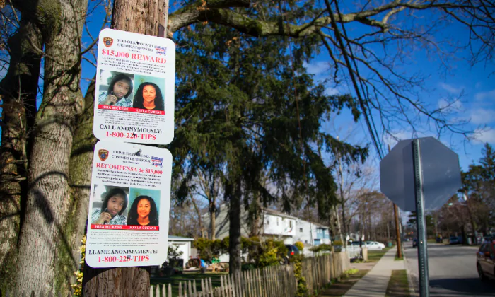 A sign offering a reward for information about the murders of Nisa Mickens and Kayla Cuevas, near Brentwood High School in Brentwood, Suffolk County, N.Y., on March 29, 2017. (Samira Bouaou/The Epoch Times)