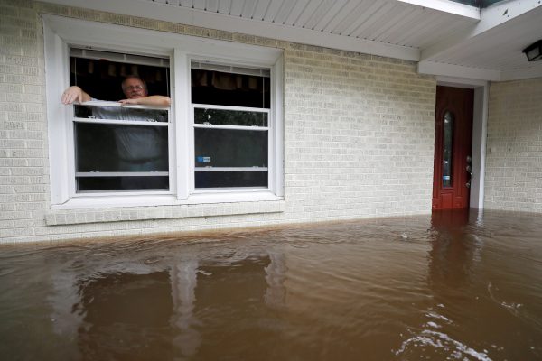 Man-peers-out-the-window-of-his-flooded-home