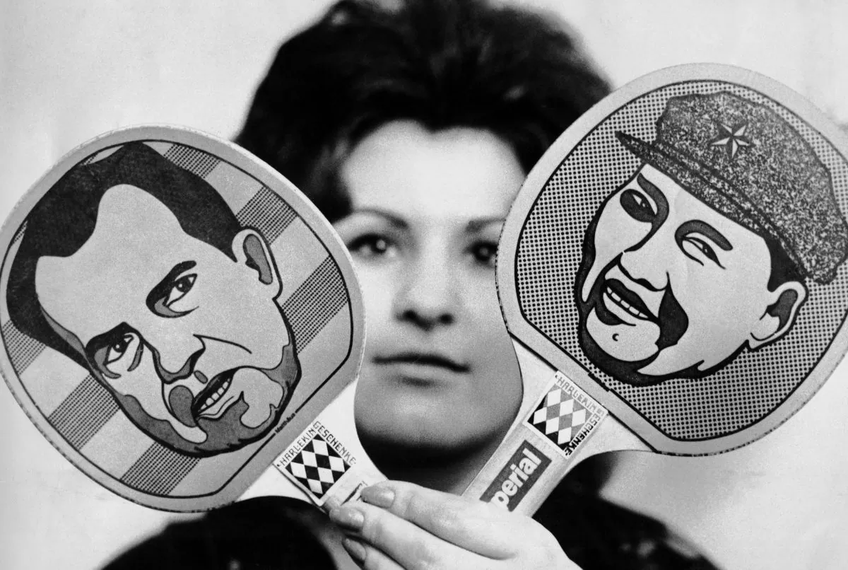 A woman holds up ping-pong paddles with U.S. President Richard Nixon and Chinese leader Mao Zedong caricatures on them, as a reference to Nixon’s “ping-pong diplomacy” with the Chinese Communist Party, in Dortmund, Germany, on Nov. 5, 1971. (AP Photo)