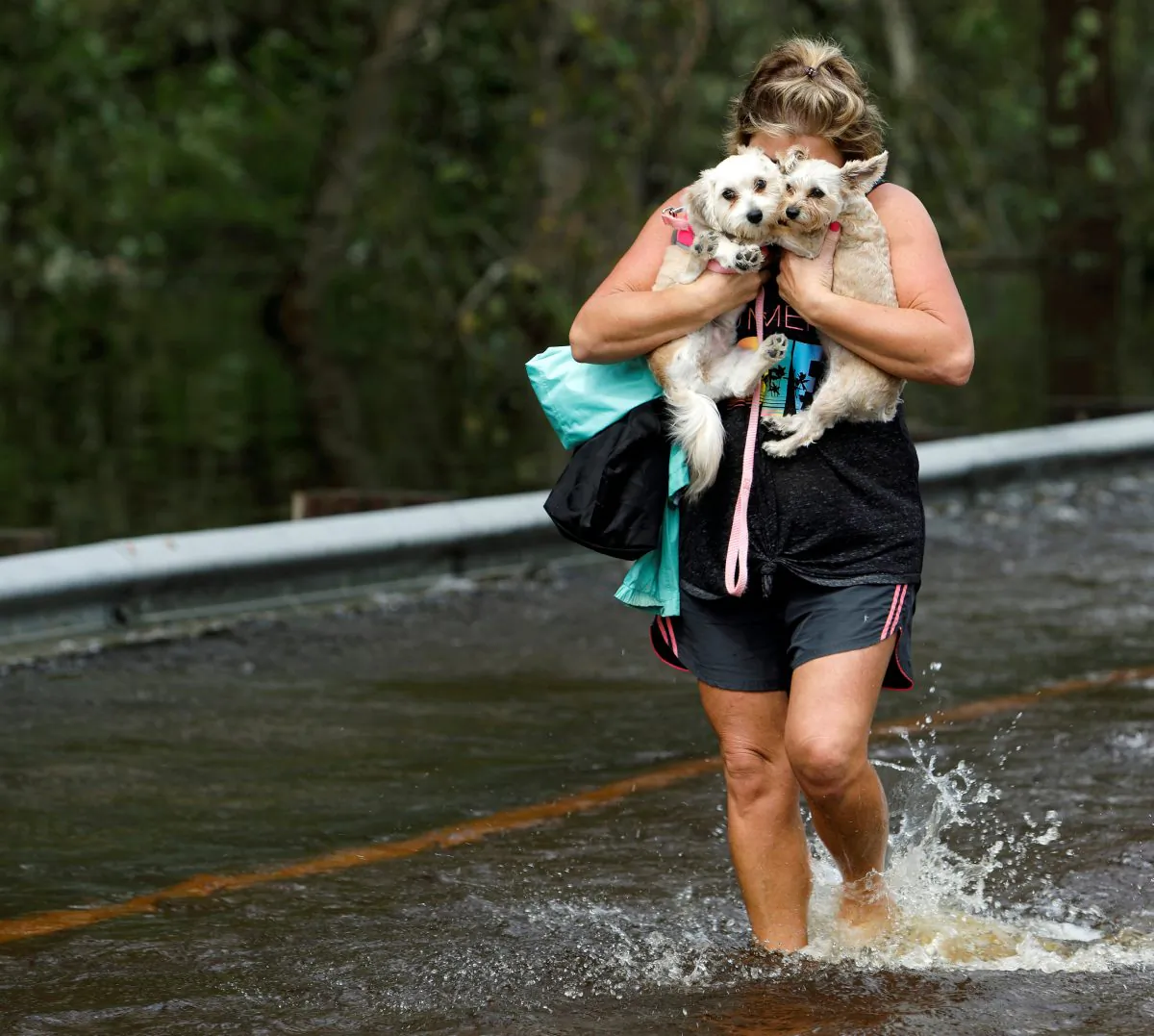 Lisa Shackleford hugs her pet dogs Izzy (L) and Bella as she wades through flood waters to safety while the Northeast Cape Fear River breaks its banks in the aftermath Hurricane Florence in Burgaw, North Carolina, U.S., September 17, 2018. (Reuters/Jonathan Drake)