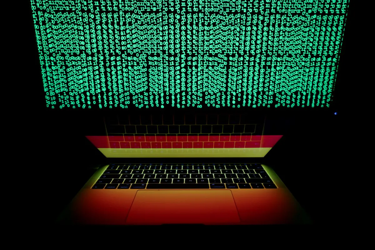 A German flag is seen on the laptop screen in front of a computer screen on which cyber code is displayed in this photo taken on March 2, 2018. (Kacper Pempel/Reuters)