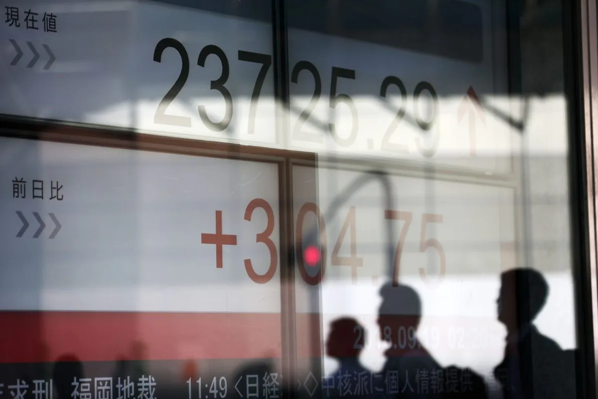 Shadows of pedestrians are seen on a stock indicator board for the Tokyo Stock Exchange in Tokyo on Sept. 19, 2018. (Behrouz Mehri/AFP/Getty Images)