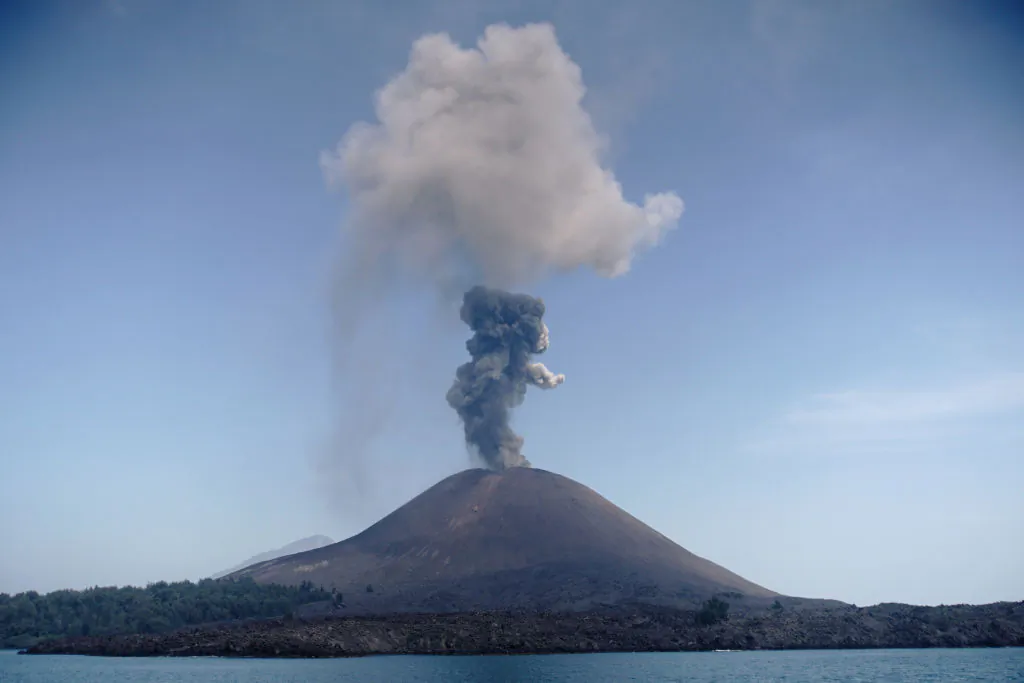 The Anak Krakatau volcano in Indonesia spews a plume of ash into the sky as molten lava streams down from its summit on July 18, 2018. (Ferdi Awad/AFP/Getty Images)