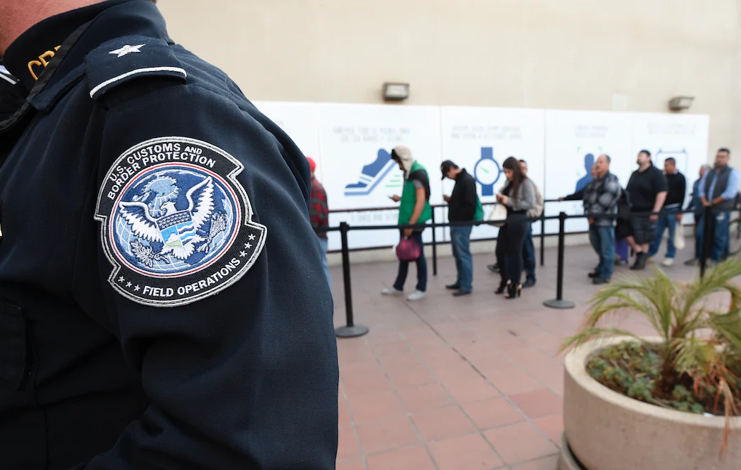 Pedestrians crossing from Mexico into the United States at the Otay Mesa Port of Entry wait in line in San Diego. The Trump administration is proposing rules that could deny green cards to immigrants if they use Medicaid, food stamps, housing vouchers and other forms of public assistance. The Department of Homeland Security said on Sept. 22, 2018, that current and past receipt of certain public benefits above thresholds will be considered "a heavily weighed negative factor" in granting green cards as well as temporary visas. (By Denis Poroy/AP)