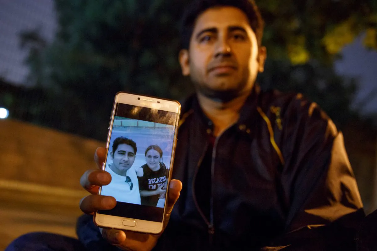 Pakistani businessman Mirza Imran Baig shows a picture of him and his wife, Mailikemu Maimati, outside the Pakistani embassy in Beijing on Sept. 25, 2018. (Thomas Peter/Reuters)