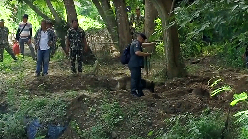Police use an excavator to dig
