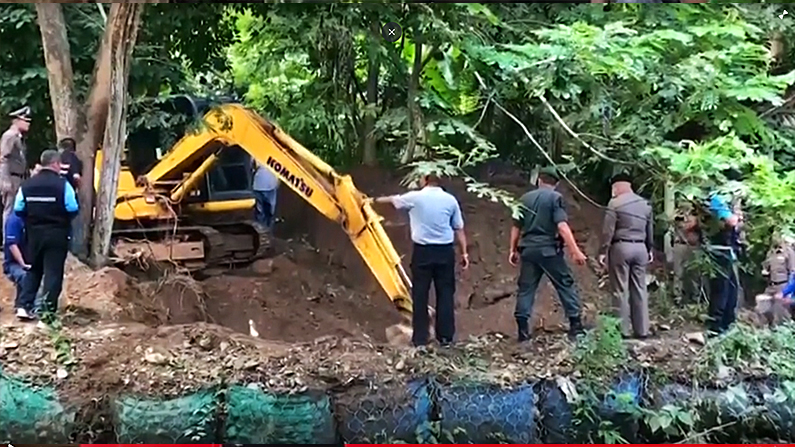 Police use an excavator to dig for the bodies