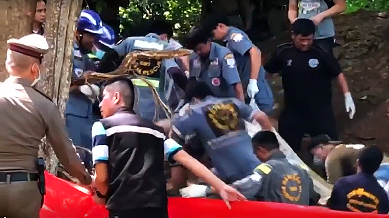 Police workers lift a body out of a grave
