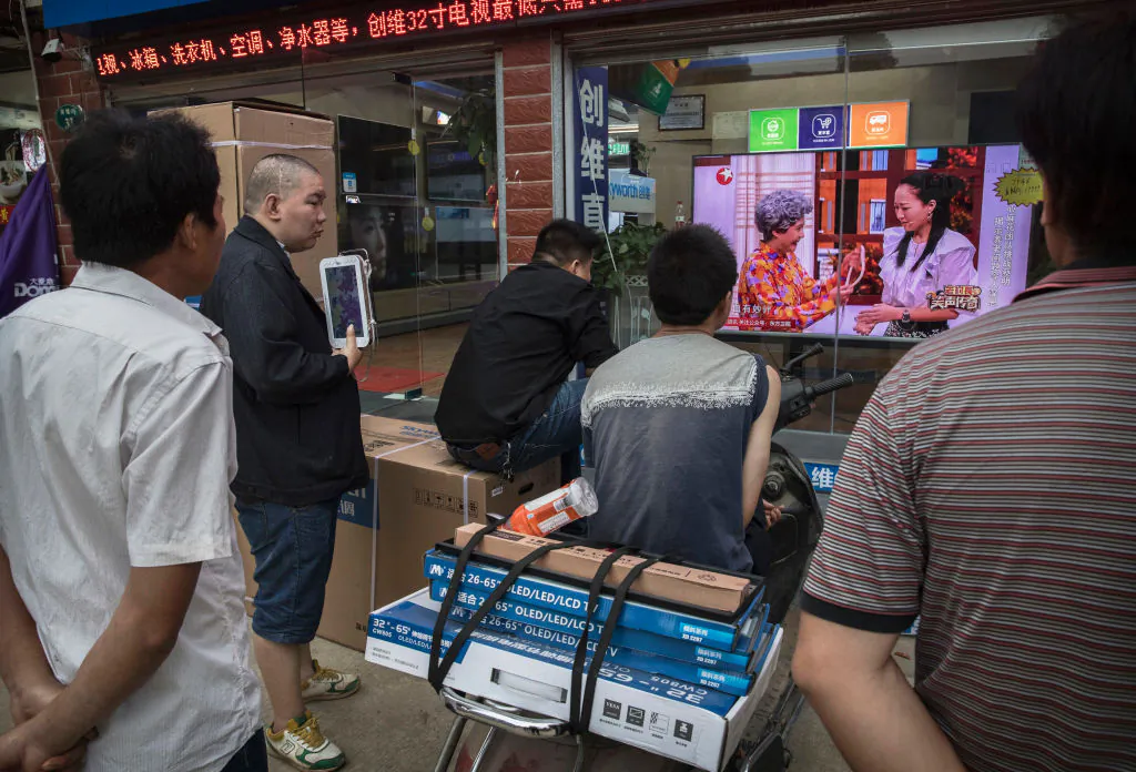 Chinese men watch a program on a large television set in the window of an electronics shop on May 15, 2017 in Wuhan, Hubei Province, China. (Kevin Frayer/Getty Images)