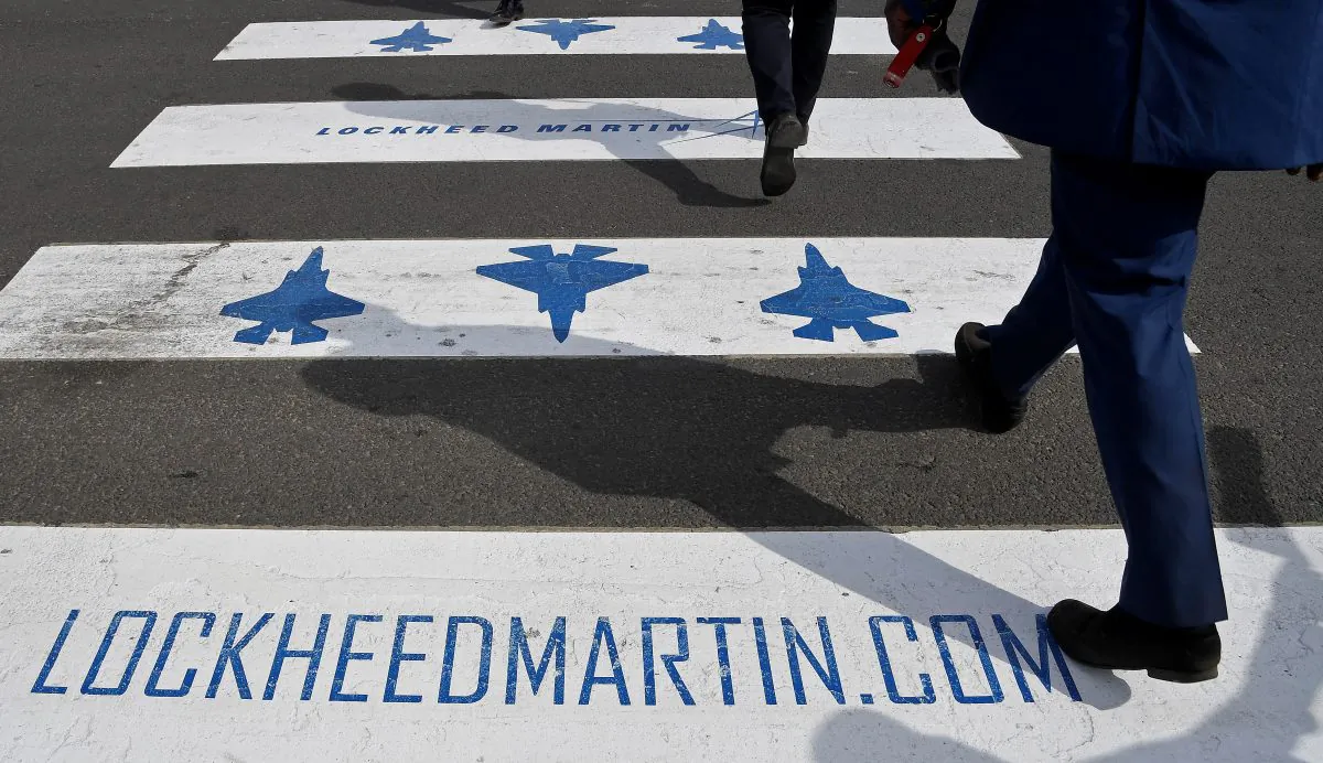 Trade visitors are seen walking over a road crossing covered with Lockheed Martin branding at Farnborough International Airshow in Farnborough, Britain, July 17, 2018. (Toby Melville/REUTERS)
