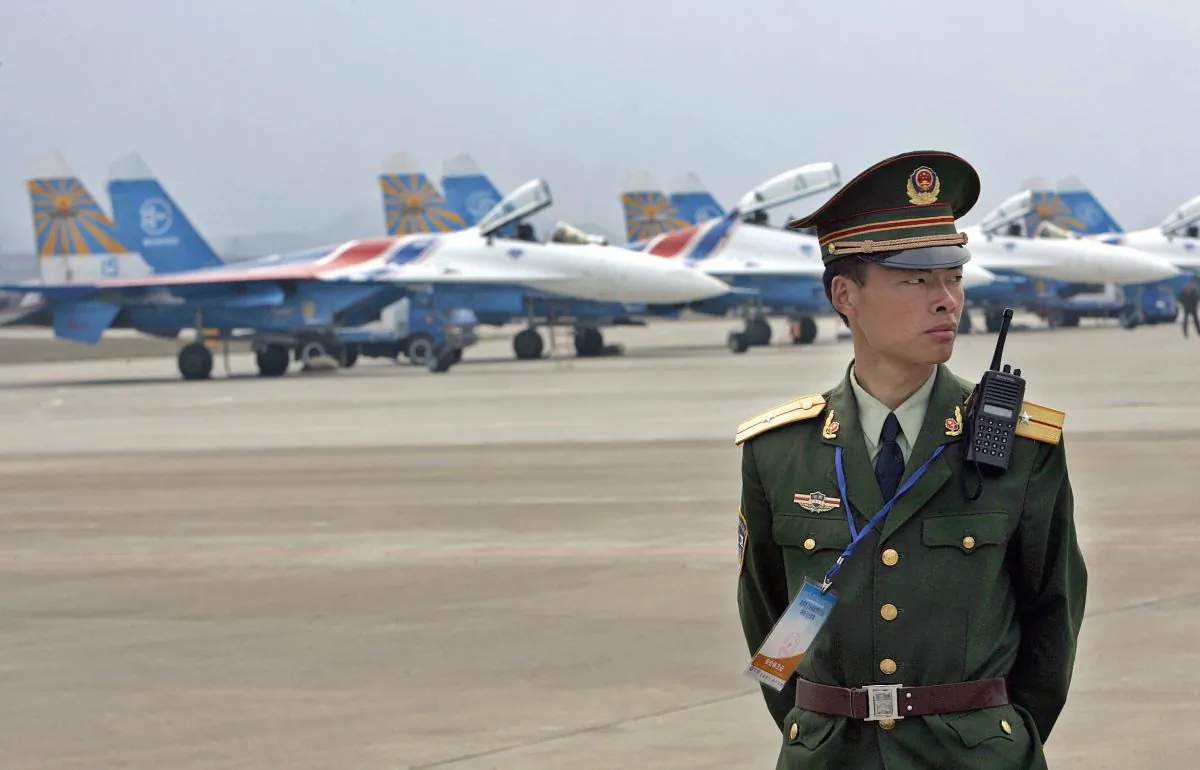 A Chinese paramilitary officer stands guard before a row of Russian Su-27 fighter jets ahead a rehearsal of aerobatics show at Zhangjiajie Lotus Airport in China's central province of Hunan, 17 March 2006. (LIU JIN/AFP/Getty Images)