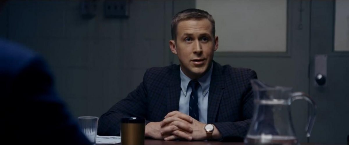 Ryan Gosling sitting at table with folded hands