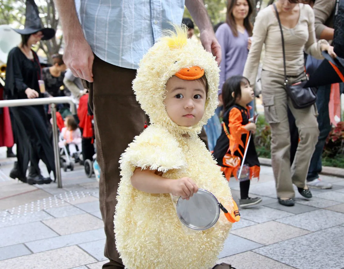 A little girl dressed as a baby chicken walks with children and their parents in costumes in Tokyo's Roppongi Hills, Oct. 28, 2006. (Yoshikazu Tsuno/AFP/Getty Images)