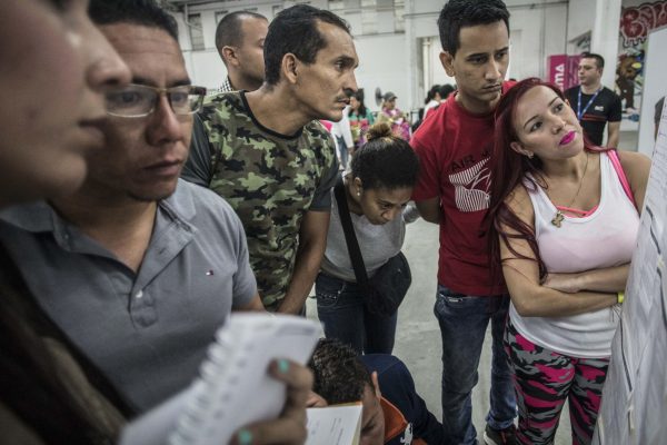 Venezuelan migrants look at job offers posted on a board during a job fair in Medellin.