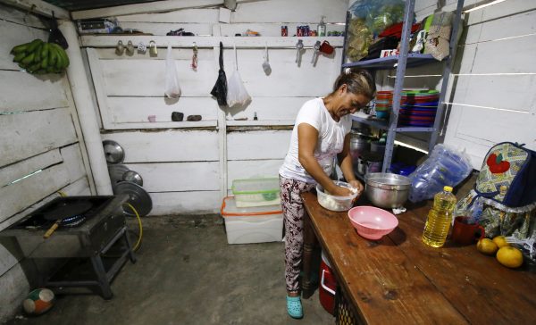 A Venezuelan migrant prepares food at an improvised shelter on the side of the road. 