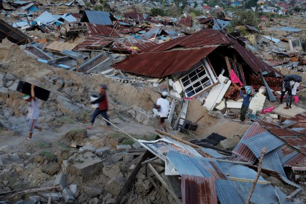 Residents carry belongings amidst debris