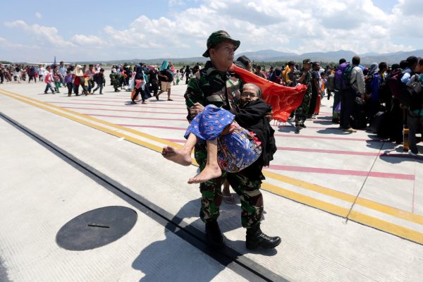 A soldier carries an elderly woman