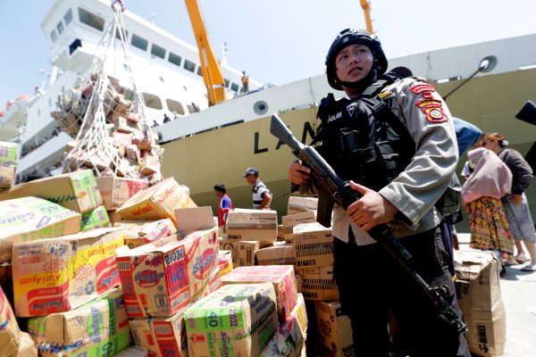 A policeman stands guard at a ship carrying relief supplies