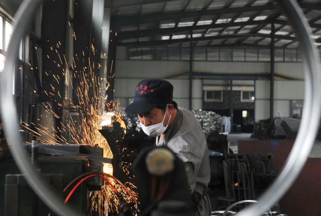 A worker welds wheel hubs of baby carriages that will be exported at a factory in Hangzhou in China's eastern Zhejiang province on June 4, 2018. - China warned the US that any deals reached during ongoing trade talks would be void if Washington went ahead with imposing tariffs on Chinese goods, as the latest round of negotiations ended on June 3 in Beijing. (-/AFP/Getty Images)
