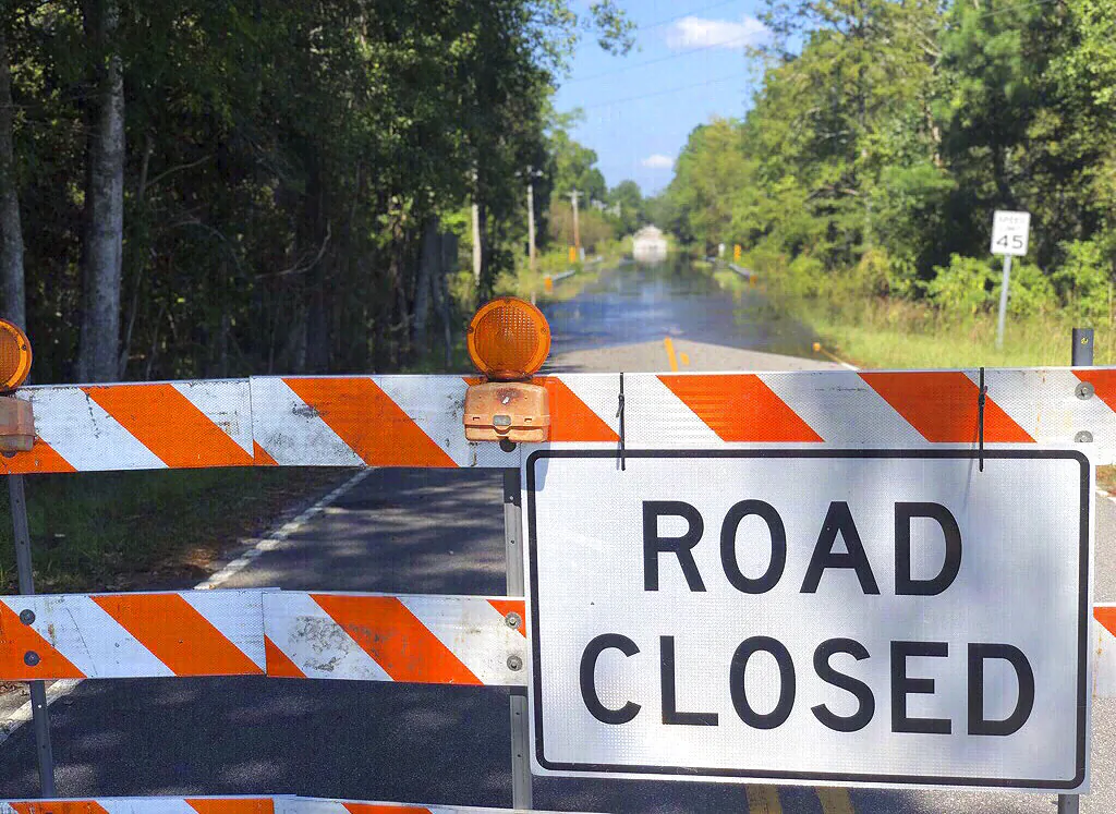 A sign stands near the Carter's Crossroads community in Georgetown County, a road adjacent to Boser Swamp is flooded over, Wednesday, Sept. 26, 2018, in Georgetown County, S.C. This is one of many lowlying areas in this and other nearby farming communities where roads are blocked off days after the rains of Florence have stopped. (Meg Kinnard/AP Photo)