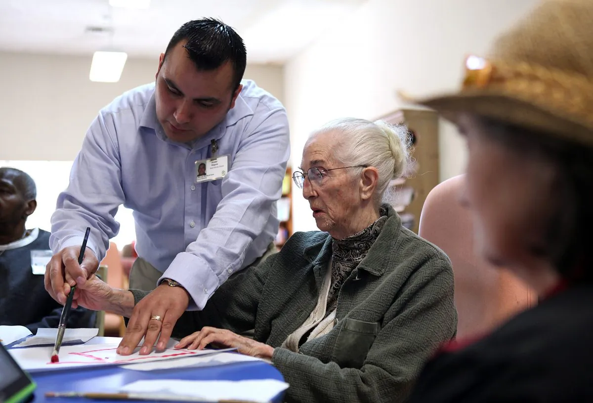 Assistant activity director Audiel Segura helps Juanita Gilbert paint a picture during an activities session at the Lifelong Medical Marin Adult Day Health Care Center on Feb. 10, 2011, in Novato, Calif. (Justin Sullivan/Getty Images)