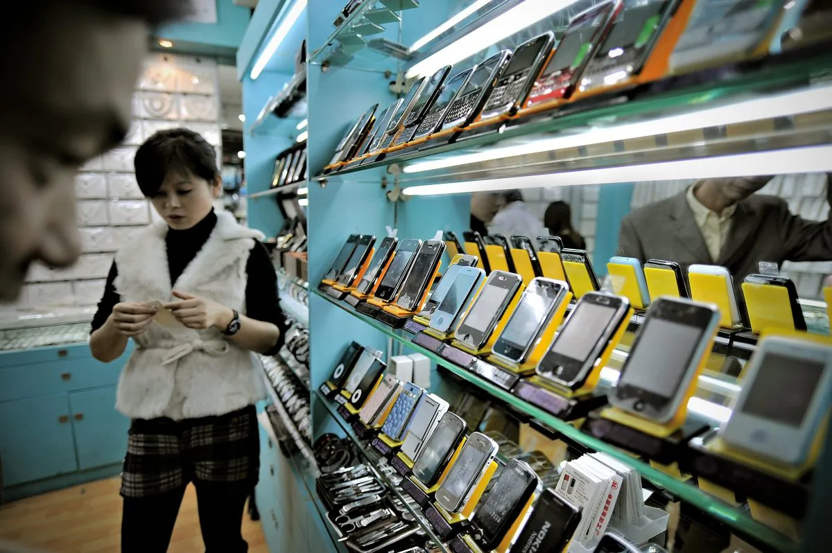 This picture taken on November 13, 2009 shows a man (L) looking at fake iPhones displayed in a shop at a market known for counterfeit US goods and housed in the metro station connected to the Science and Technology Museum in Shanghai. (PHILIPPE LOPEZ/AFP/Getty Images)