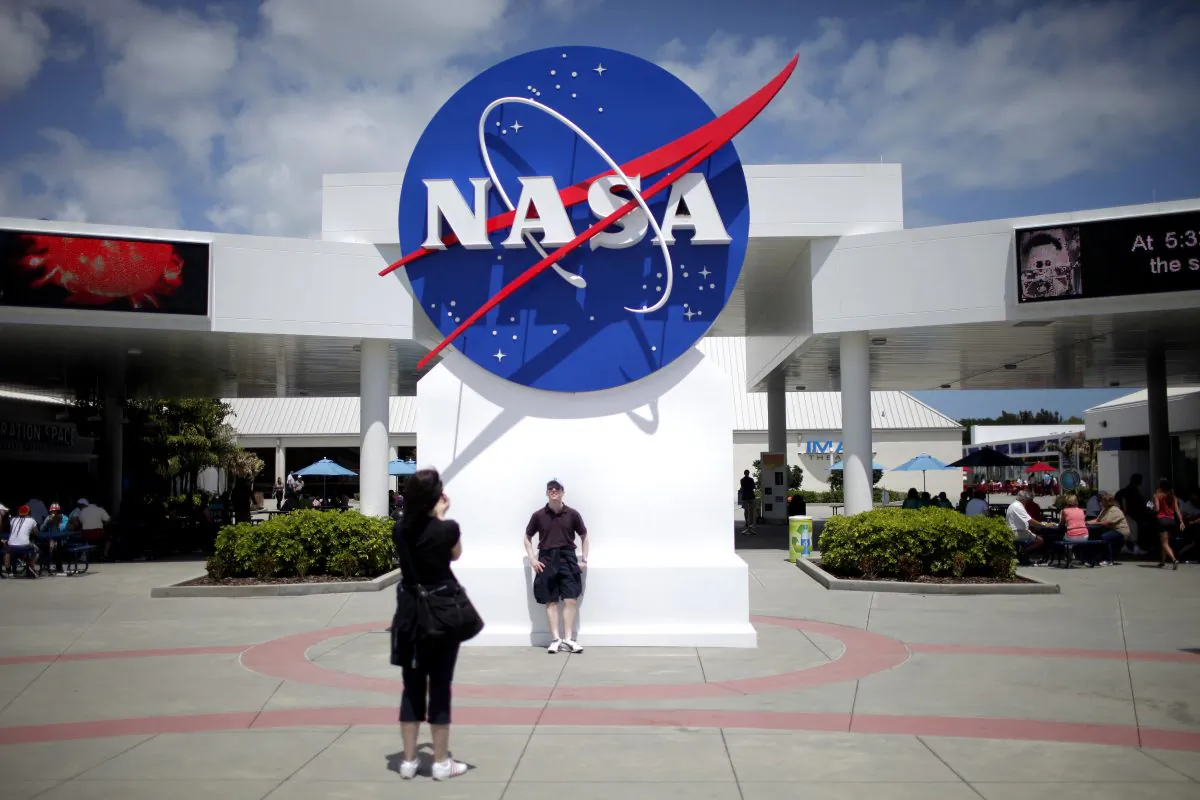 Tourists take pictures of a NASA sign at the Kennedy Space Center visitors complex in Cape Canaveral, Fla., on April 14, 2010. (Carlos Barria/Reuters)