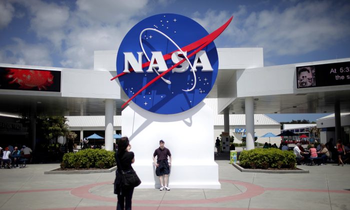 Tourists take pictures of a NASA sign at the Kennedy Space Center visitors complex in Cape Canaveral, Fla., on April 14, 2010. (Carlos Barria/Reuters)