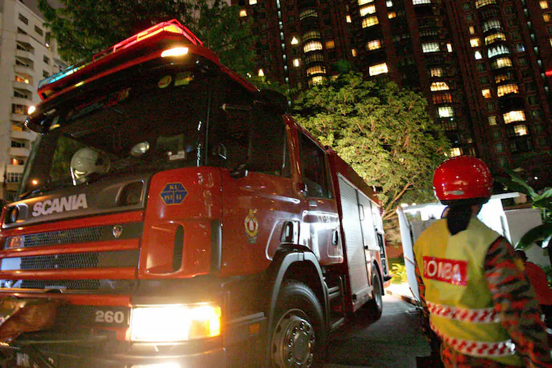 A member of the Malaysian Fire and Rescue Department (R) waits beside a fire truck at the entrance of the Philippine Embassy in downtown Kuala Lumpur in 2005. (Tengku Bahar/AFP/Getty Images)
