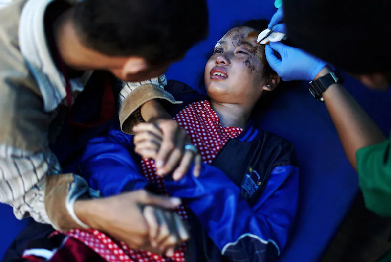 A father holds his daughter's hand in a hospital as she receives medical treatment for injuries sustained from the earthquake and tsunami in Palu, Central Sulawesi, Indonesia, Oct. 4, 2018. (Reuters/Athit Perawongmetha)