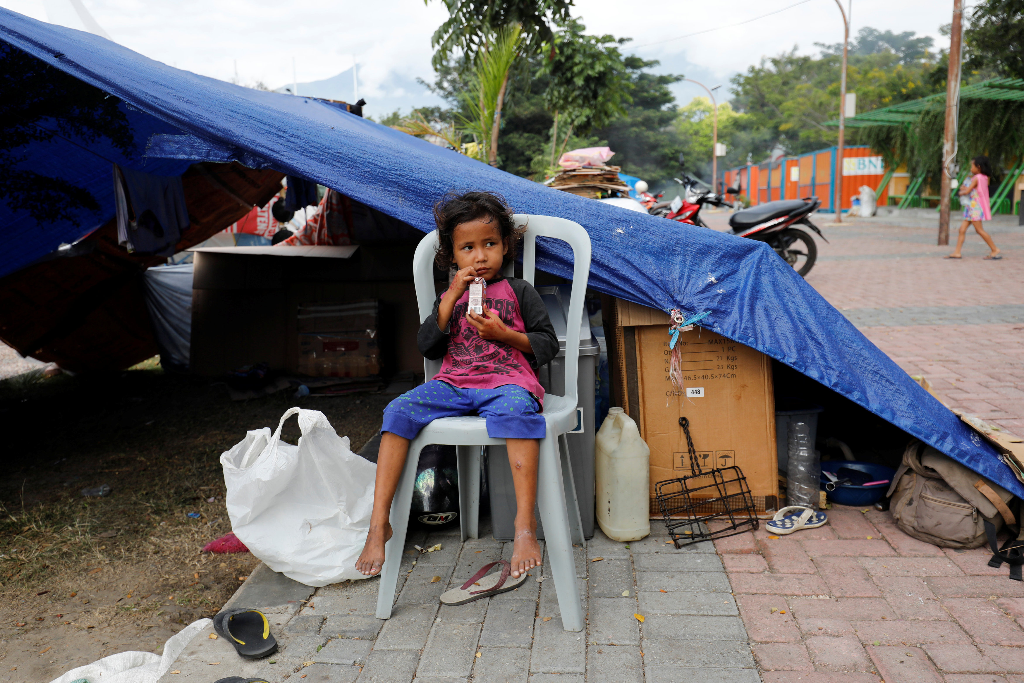 A boy sits outside his tent in a camp for displaced victims of the earthquake and tsunami in Palu