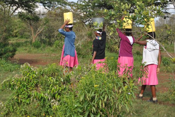 Girls who have taken refuge at the Samburu Girls Foundation carry buckets of water from a river.