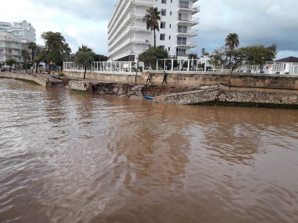 People walk along damaged waterfront