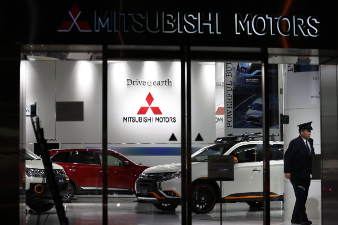 A security worker walks past a Mitsubishi Motors Outlander plug-in hybrid sport utility vehicle displayed at the company's headquarters in Tokyo on April 20, 2016. (Tomohiro Ohsumi/Getty Images)