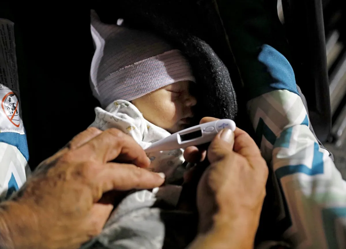 Wilmer Capps takes the temperature of his two-day-old son Luke while preparing with his wife Lorrainda Smith to spend the first night out of the hospital in a parking lot in Panama City, Fla. on Oct. 15, 2018. (AP Photo/David Goldman)