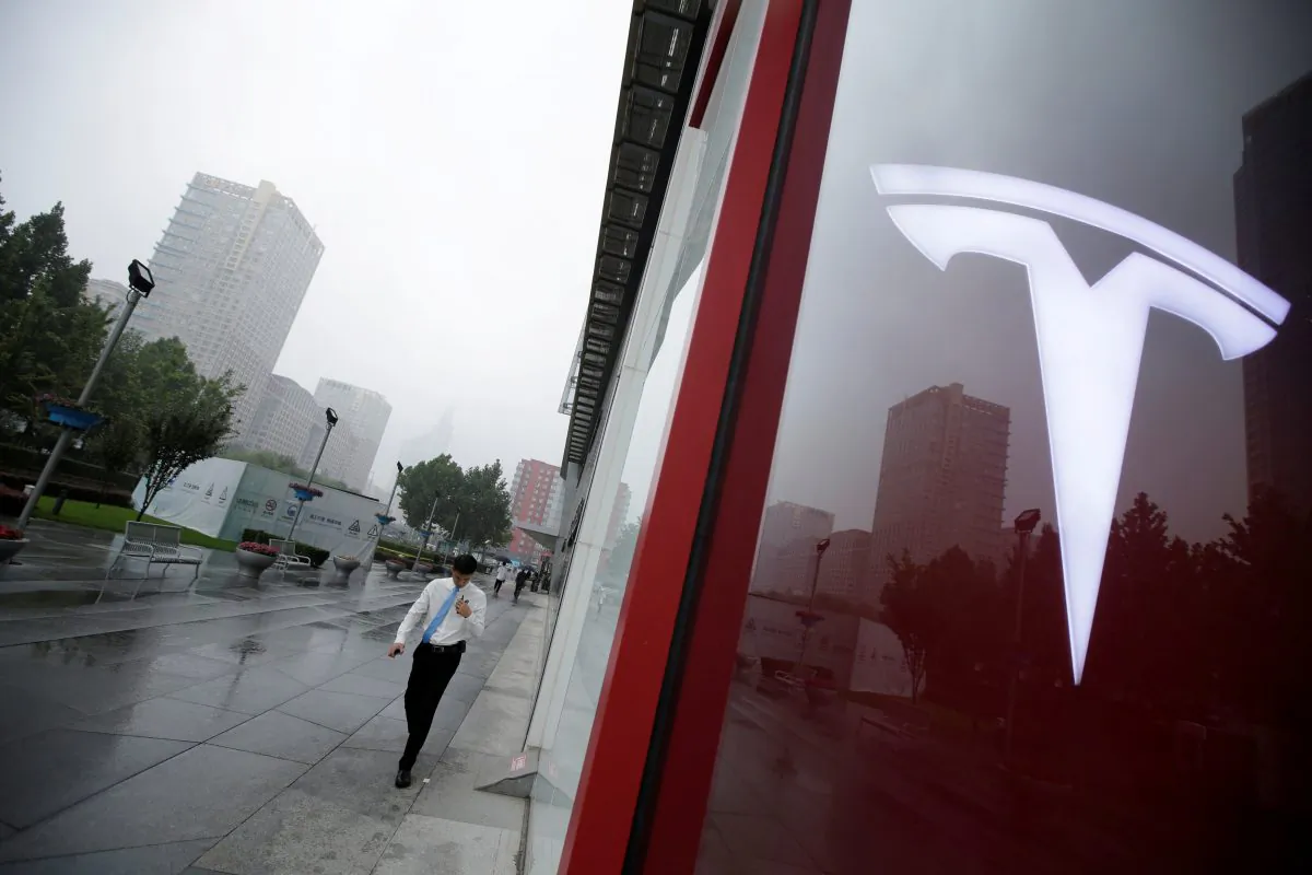 A man walks near a logo of Tesla outside its China headquarters at China Central Mall in Beijing, China Jul. 11, 2018. (Reuters/Jason Lee)