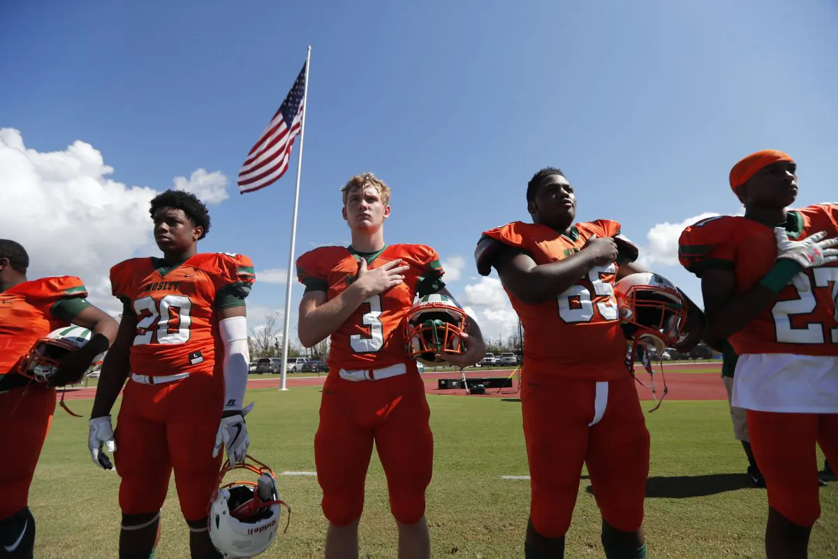 Mosley High football players hold their hands to their heart during the the national anthem, before the start of their football game against Pensacola, in the aftermath of Hurricane Michael in Panama City, Fla.,, Oct. 20, 2018. (AP Photo/Gerald Herber