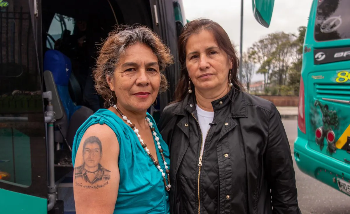 María Doris Tejada (L), showing a tattoo of her missing son on her arm, and Jacqueline Castillo, the legal representative of Madres de Soacha, or Mothers of Soacha, who lost her brother in the phenomenon most commonly known as the “false positives” scandal, pose for a photo on Oct. 13, 2018, in Bogota, Colombia, before going on a 16-hour bus ride to the other side of the country to commemorate their loved ones who lost their lives in the scandal. (Luke Taylor/Special to The Epoch Times)